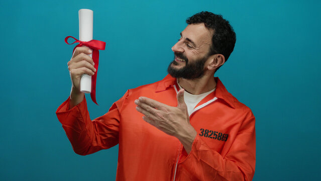 Man in orange prison jumpsuit smiling holding diploma against blue background symbolizing education in prison. - Powered by Adobe