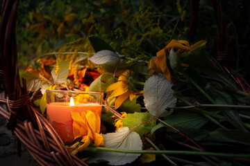 Warm glow enhances peaceful evening, Rustic scene illuminated by gentle amber flames atmosphere, Basket with candles and flowers creates calming seasonal setting