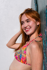 Naklejka premium Close-up of woman leaning against wall in floral bikini top