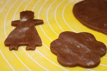 Making shapes with dough on a yellow surface in a kitchen during a baking session