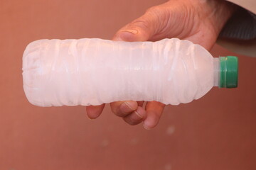 Hand holding a bottle of frozen water