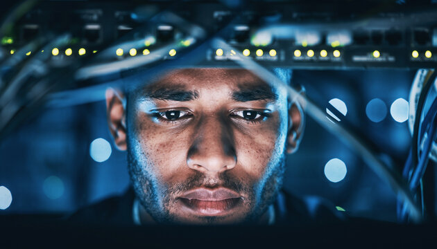 A focused IT professional working in a data center, surrounded by glowing server racks and network equipment.