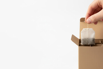 Taking a tea bag out of a cardboard box. Space for text.