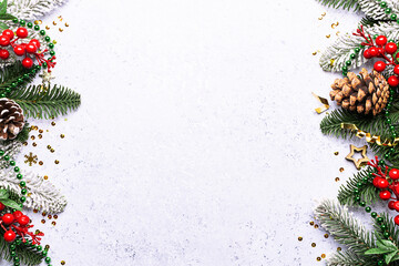 Festive Christmas and New Year frame made with fir tree branches, pine cones and golden decorations on light marble background with copy space for your design.