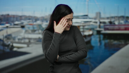 Brunette woman making expressions at a port with ships docked, highlighting emotions and maritime setting.