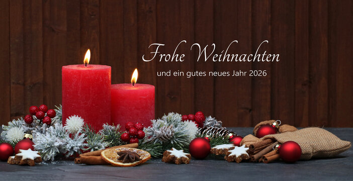 Weihnachtskarte: Brennende rote Kerzen mit Weihnachtsschmuck und Tannenzweigen vor einem Holzhintergrund. Auf dem Holz steht der Gruß frohe Weihnachten und ein gutes neues Jahr 2026.