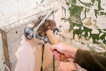 A plumber is dismantling a faucet in the bathroom.