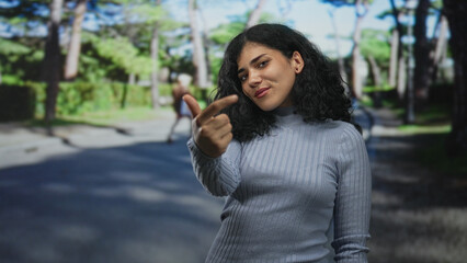 Woman points finger at camera on street showing nose piercing and turtleneck; casual direct confidence.