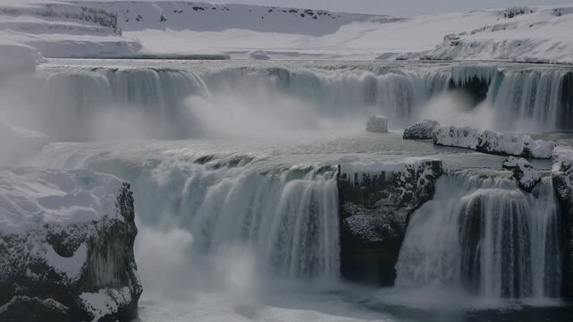 A stunning waterfall cascades over rocks in a winter wonderland. The water is partially frozen, adding to the beauty of the scenery. Stock Video