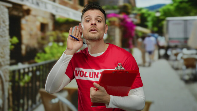 Volunteer man listens attentively holding clipboard in vibrant urban street setting featuring colorful backgrounds and casual atmosphere on a sunny day reflecting community spirit.