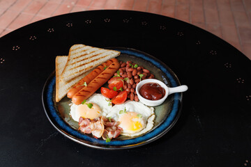 Colorful Breakfast Plate With Eggs, Sausage, Beans, Tomatoes, Bacon And Toast On Dark Plate