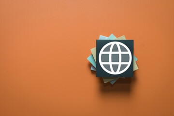 World globe icon on sticky note representing global business, international communication, worldwide network, and internet connection concept on orange background with copy space.