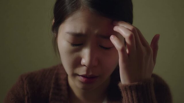 A woman experiencing distress, possibly a headache or stress, with a worried expression Stock Video