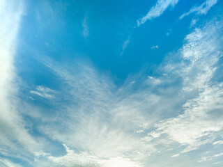 Bright blue sky with scattered soft clouds and gentle atmospheric texture.
