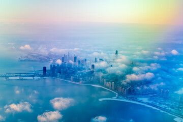 Aerial view of Chicago, Illinois, featuring iconic skyscrapers like Willis Tower and John Hancock Center amidst cloud cover. The skyline is partially obscured by clouds, creating an ethereal scene