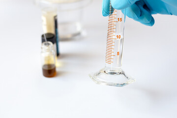 A scientist holds a graduated cylinder containing exactly 10 ml of solvent to prepare the mobile phase for Thin Layer Chromatography (TLC) analysis.