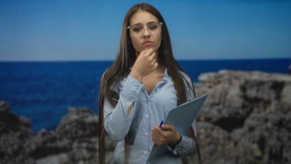 Woman with clipboard touches chin and later points finger in studio; thoughtful analysis notes summary.