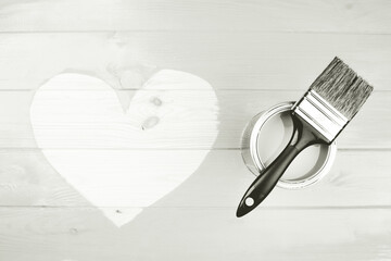 Paint can and brush resting on wooden planks with a hand painted heart shape. Concepts of love,...