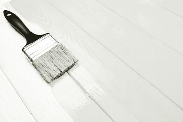 Paintbrush with white paint coating wooden planks, transforming old wood into a fresh, clean surface during home improvement. Color of 2026 year dancer in the white cloud