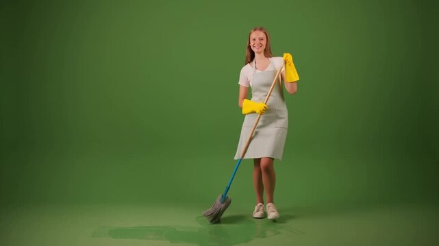 A cheerful woman smiling while cleaning, holding a mop in hand. She wears yellow gloves, ready to keep things tidy Stock Video