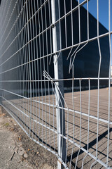 Damaged metal fence panel showing bent wire detail outdoors.