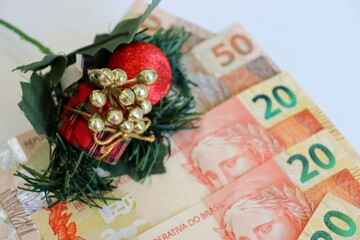 Brazilian real banknotes and smartphone with empty screen and Christmas ornaments. Place for text. Brazilian economy in December.