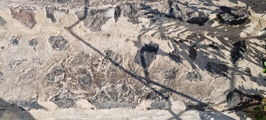 Stone wall with shadows on the surface during the day in a sunny outdoor setting in a garden