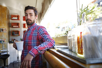 Portrait, man and relax with drink at coffee shop to start day, peace and calm morning. Male person, espresso and beverage for weekend break, customer experience and unwind with wellness liquid