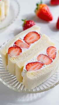 Delicate Japanese strawberry fruit sando on a glass plate, showcasing perfectly sliced berries fluffy whipped cream between soft shokupan slices for a pastel cafe-style dessert with a clean