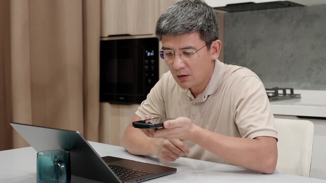 Focused person applies voice command on his mobile phone as he works on laptop. Concept of digital communication, AI assistant, remote work, voice control technology and modern home office.
