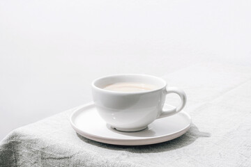 A cup of coffee on a table with tablecloth. Minimal still life. Illustration for the 2026 Color of the Year: Cloud Dancer