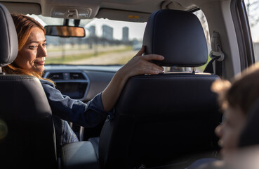 Woman talks to child in back seat of car on road