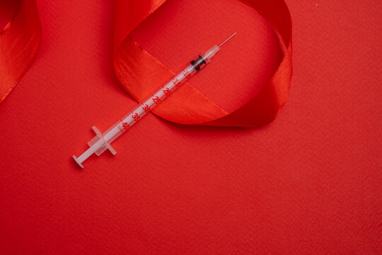 Red ribbon and syringe symbol. Global health awareness. - Powered by Adobe