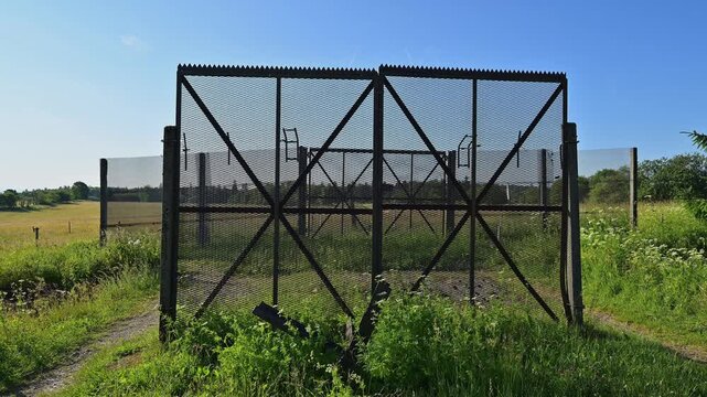 Grenzzaunzaun der ehemaligen Innerdeutsche Grenze, umgeben von gr&uuml;nen Wiesen unter einem klaren blauen Himmel, Sommer, Fladungen, Frankenheim, Hohe Rh&ouml;n, Rh&ouml;n, Hessen, Th&uuml;ringen, Bayern, Deutschland 