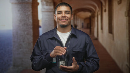 Young hispanic man police detective wearing a badge on a lanyard, smiling and rubbing hands while...