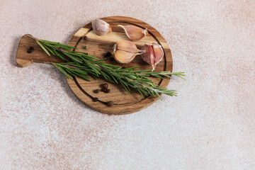 Fresh rosemary and garlic on a wooden cutting board in a kitchen setting during daytime