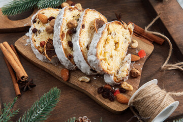 Delicious slices of sweet stollen cake with nuts and fruits on a wooden board in a kitchen setting