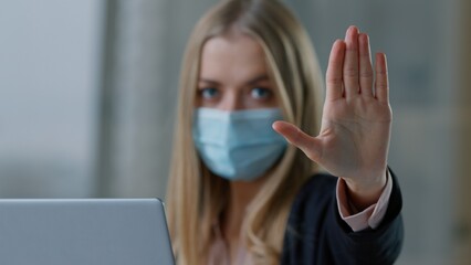 Caucasian business woman in medical face mask with laptop showing stop gesture no palm sign businesswoman girl female employer hand not never forbid deny reject keep distance pandemic covid19 rules