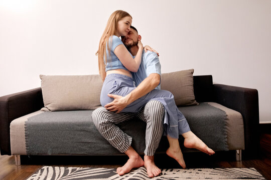 Couple sitting on a couch, embracing and enjoying intimate moments at home in the evening