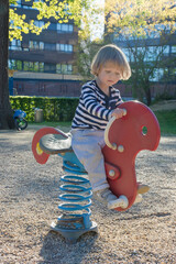 Happy little child boy having fun playing with colorful wooden toys outdoors in the park, beautiful summer sunny day in children playground. Selective focus