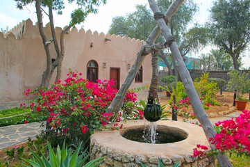 Traditional stone house and well in the front garden at the Heritage village, Abu Dhabi, United Arab Emirates.