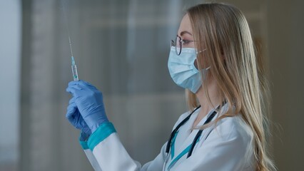 Caucasian woman doctor preparing vaccination holding syringe for injection covid19 vaccine virus...