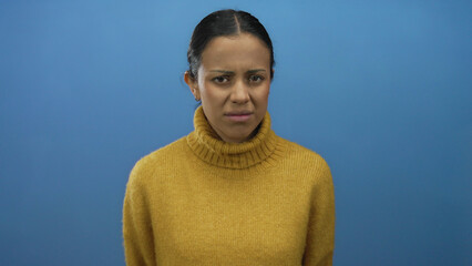 Woman expressing various emotions in front of a blue wall wearing a yellow sweater, showcasing...