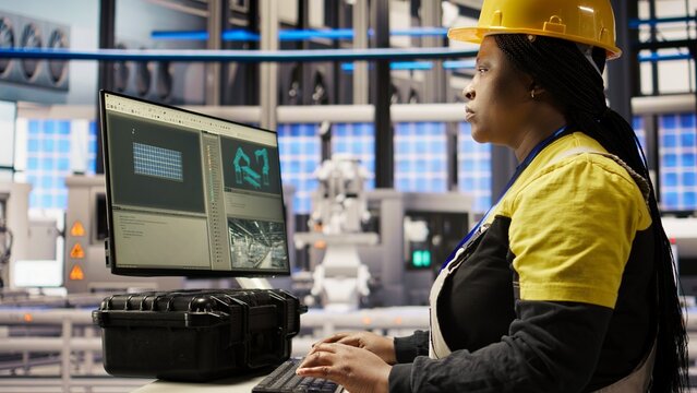 Technician in industrial plant monitors production equipment using PC software, diagnosing malfunctions. Factory employee coordinates repair tasks on assembly lines using computer program, camera A
