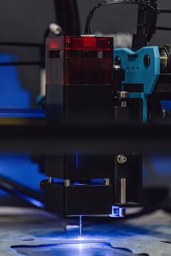 Industrial laser cutting of paronite gasket material. CNC machine cutting sheet material with a blue beam. High precision manufacturing process of sealing parts for engineering and engines.