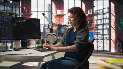Software developer at agency office coding on her computer, creating a software and works on implementing algorithms. IT expert building applications with a programming interface. Camera A.