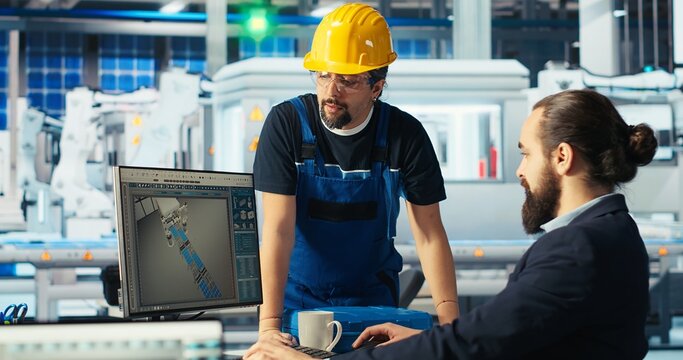 Photovoltaics factory manager showing engineer on PC screen how to adjust system parameters. Specialist showing staff member how to optimize energy supply in solar panel manufacturing plant, camera B