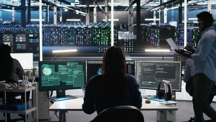 Server hub admin responds to cyberattack attempting to access confidential data while securing hardware systems. Data center worker fighting malware intrusion during security incident, camera A