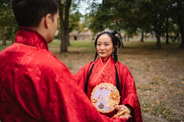 Multicultural couple celebrating Asian wedding tradition in park