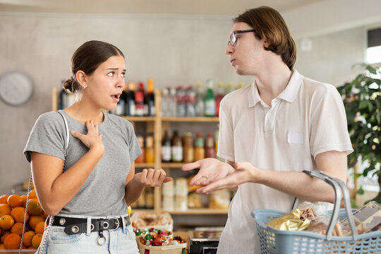 Married couple quarreling in the supermarket while buying food for the week Husband and wife sorting things out against the background of food shelves
